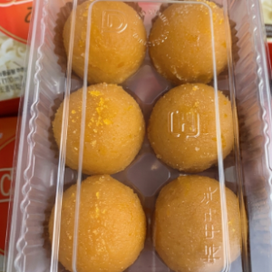 A clear plastic tray packaging containing a 6 pack of frozen orange motichoor laddus.
