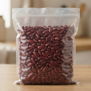 Front view of a clear, unlabeled resealable plastic stand-up pouch filled with 1kg of glossy dried red kidney beans, resting on a clean wooden table with a blurred kitchen background.