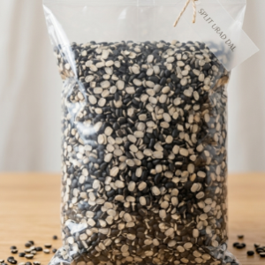 A transparent plastic stand up pouch filled with clean split black gram urad dal lentils on a wooden table.
