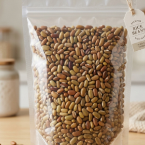 A vertical clear transparent stand up zipper pouch filled with premium unpolished whole masyang rice beans on a wooden kitchen surface.